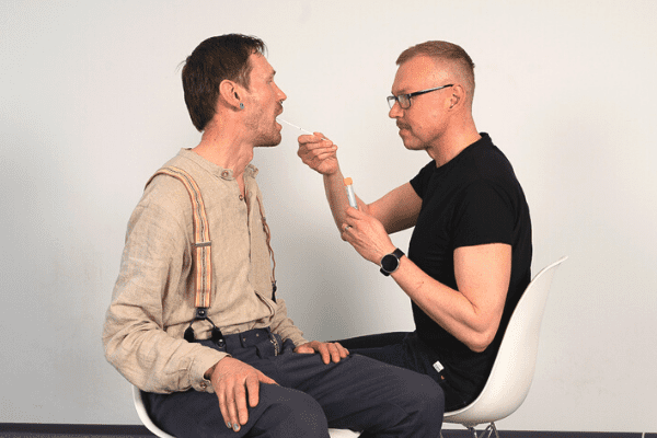 A health care professional is taking a throat swab from another person´s mouth.